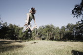 年轻女子在草地上跳跃图片素材