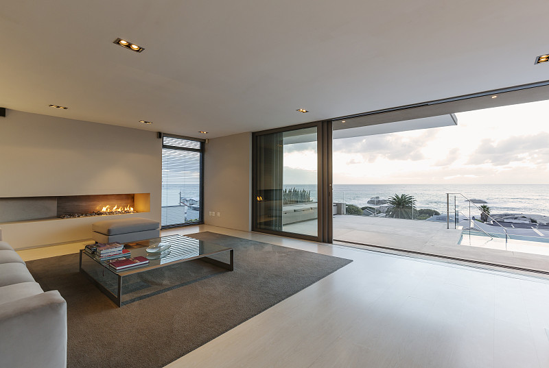 現代，極簡主義豪華客廳與燃氣壁爐和天井門打開海景和露臺圖片素材