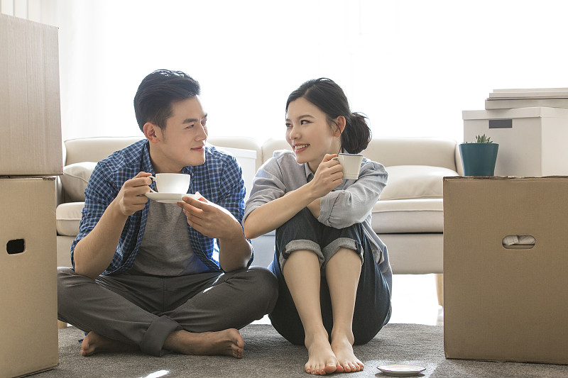 年輕情侶坐在客廳地上喝咖啡休息圖片下載