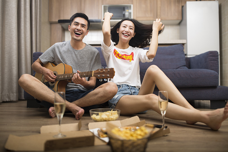 快樂的情侶在客廳演奏吉他圖片下載