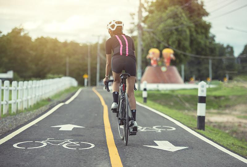 亞洲健康的自行車女孩戴頭盔騎自行車和鍛煉自行車在短跑跑道和開放的道路圖片素材