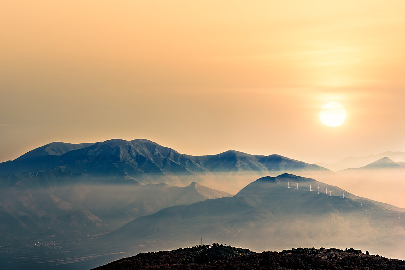 在橙色日出的山頂下有霧圖片素材