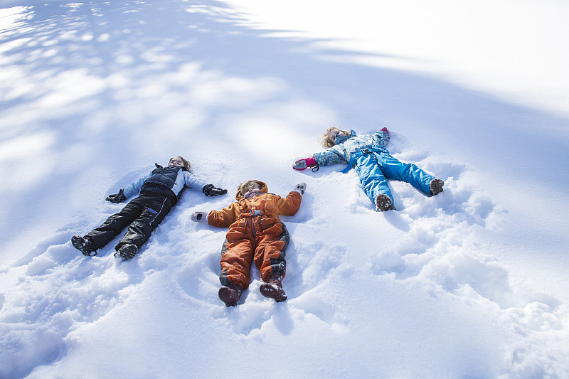 孩子們在樹影下做雪天使圖片素材