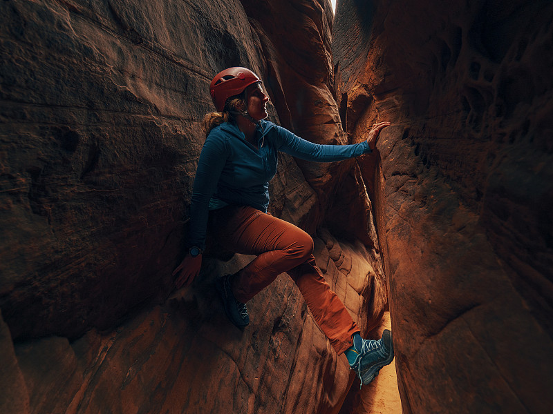 一個年輕的女人爬過狹縫峽谷圖片素材