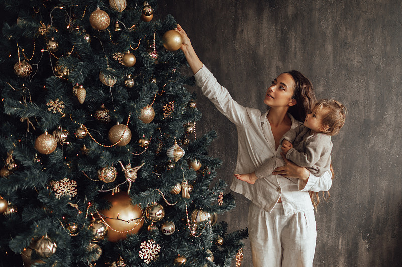 母親和女兒在家里裝飾圣誕樹。圖片素材