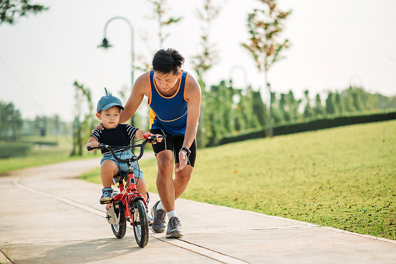 亞裔華人父親在公園教小兒子騎自行車圖片素材