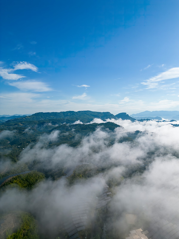 從無人機的視角看，山坡上的太陽能電池板在云霧中攝影圖片