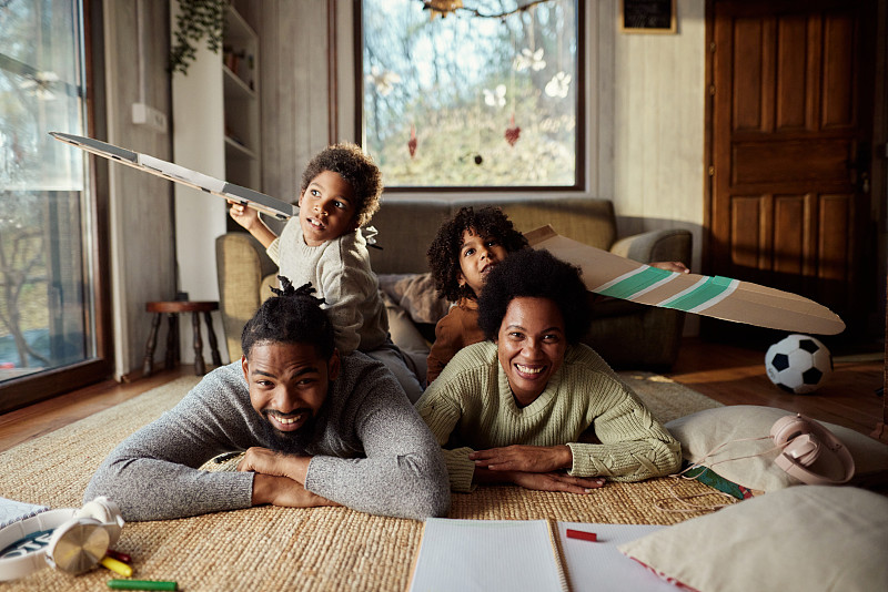 快樂的非裔美國家庭在家里的地毯上玩得很開心。圖片下載
