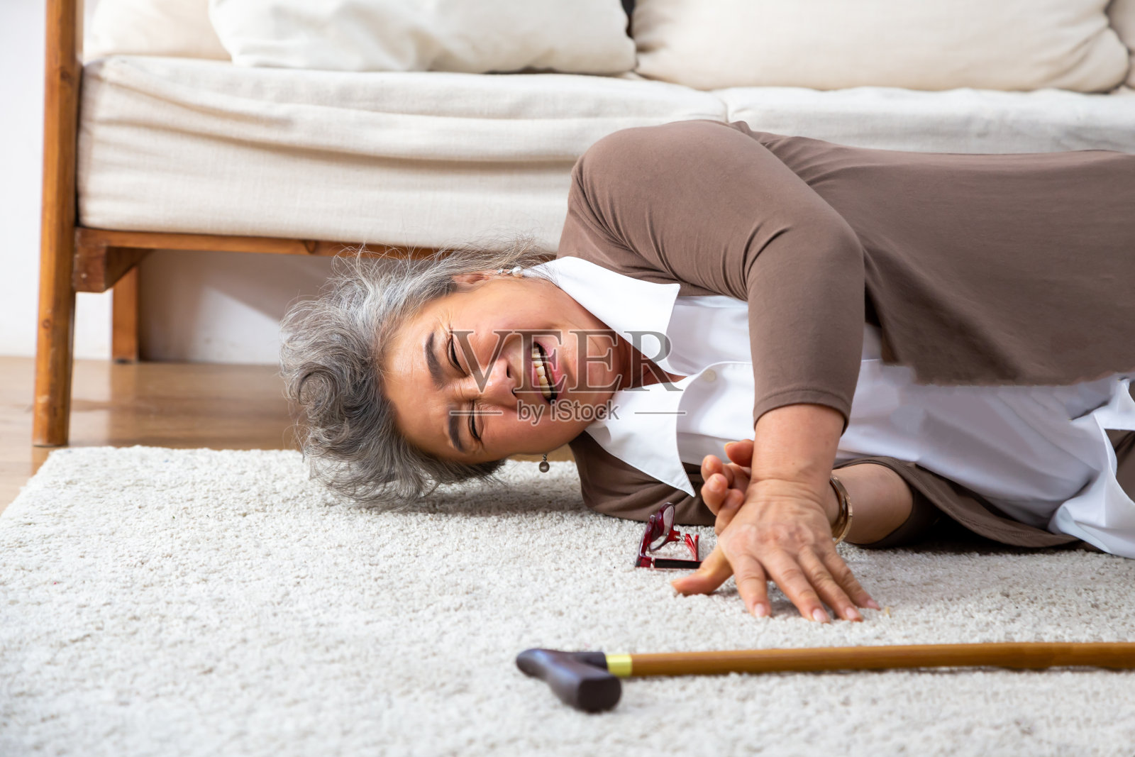 亚洲资深女性跌倒在地毯上，躺在家里客厅的地板上，跌倒的老年人的概念照片摄影图片