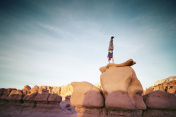 在沙漠中，一个人在户外的岩层上做倒立图片素材