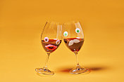 两杯红酒与拟人化的脸在黄色的背景图片素材