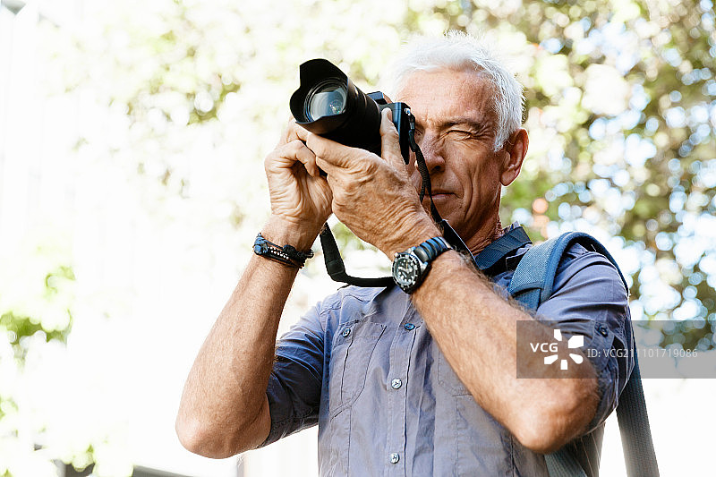 一个带着相机的老人在城里。寻找好照片图片素材