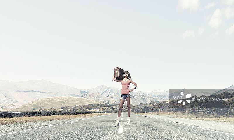 搭便车旅行。年轻复古的女人肩上扛着复古的行李图片素材