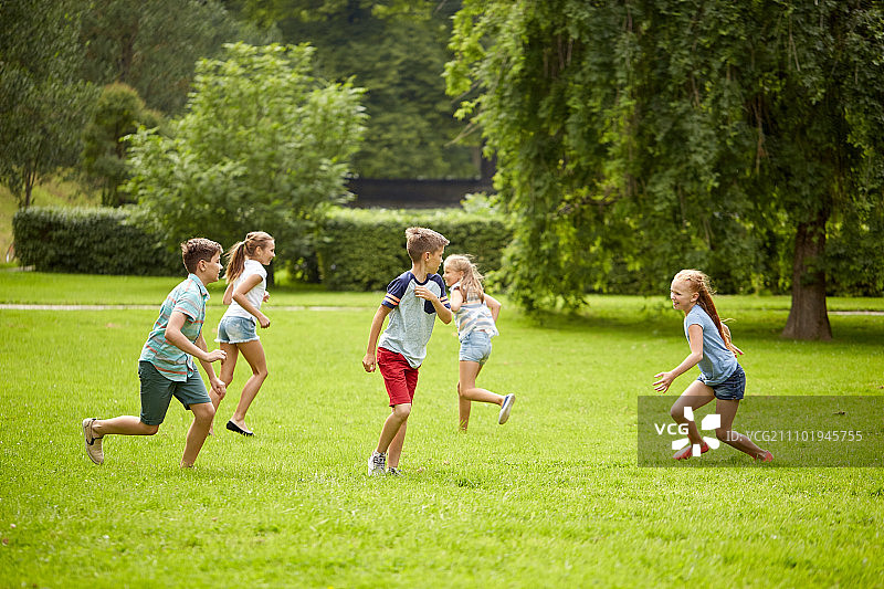 友谊，童年，休闲和人的概念-一群快乐的孩子或朋友玩追赶游戏和在夏季公园跑步图片素材
