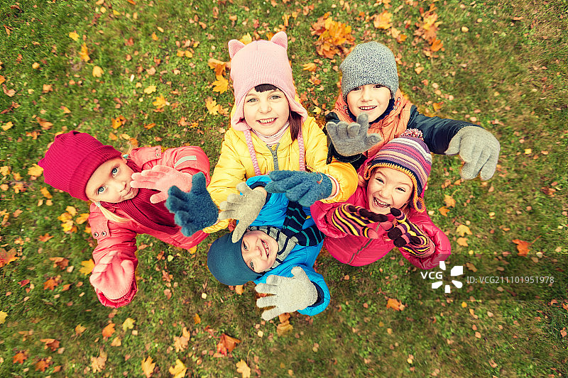 童年、休闲、友谊、人的理念——一群快乐的孩子在秋天的公园里挥手致意图片素材
