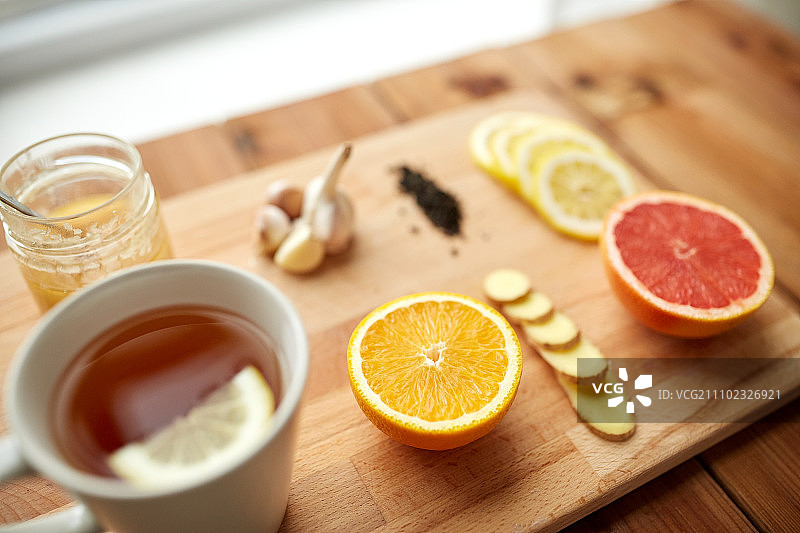 健康，传统医学，民间疗法和民族科学概念-一杯姜茶与蜂蜜，柑橘和大蒜在木制背景图片素材