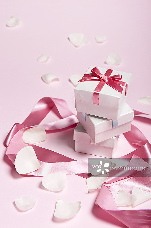 粉红色背景上有丝带和花瓣的礼品盒图片素材