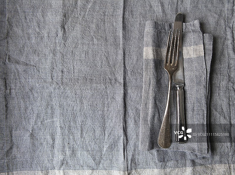 灰色亚麻布餐具与相配的灰色亚麻布餐巾和老式银刀叉图片素材
