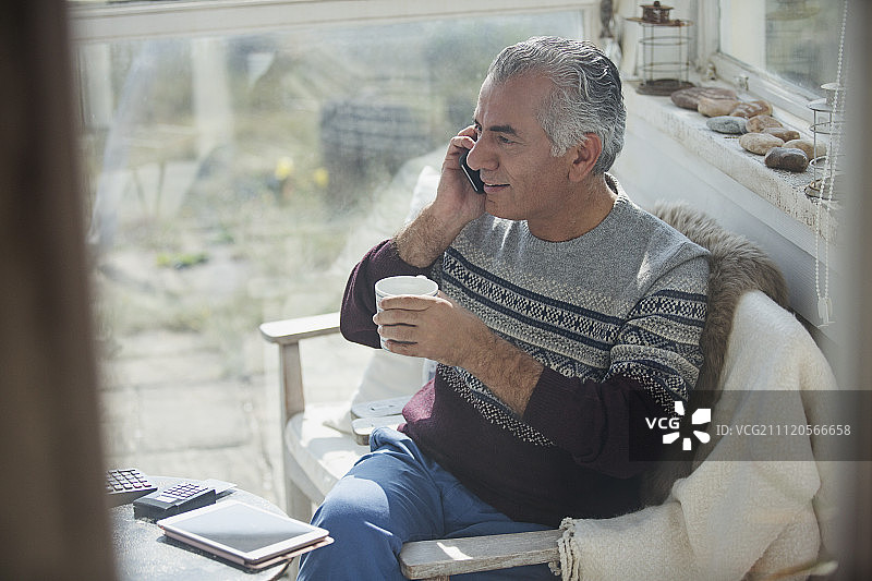 老男人在阳台上喝咖啡，打手机图片素材
