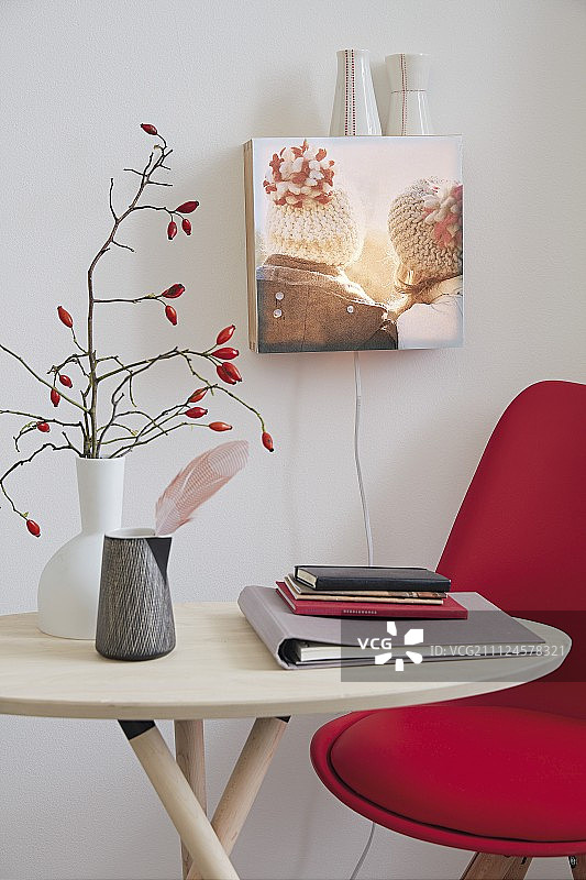 一个DIY的壁灯，由一个灯箱做成，上面有一张照片，前面有一张桌子和一把红色的椅子图片素材