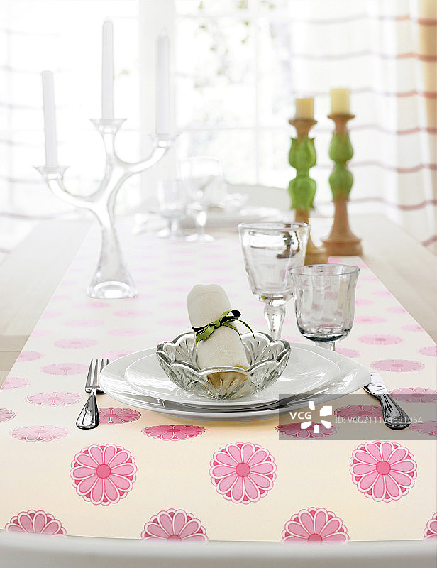 餐桌上摆放着玻璃盘子、碗和花卉图案桌布图片素材