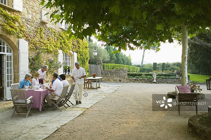 客人在宽敞的露台上吃早餐与地中海花园的乡村别墅图片素材