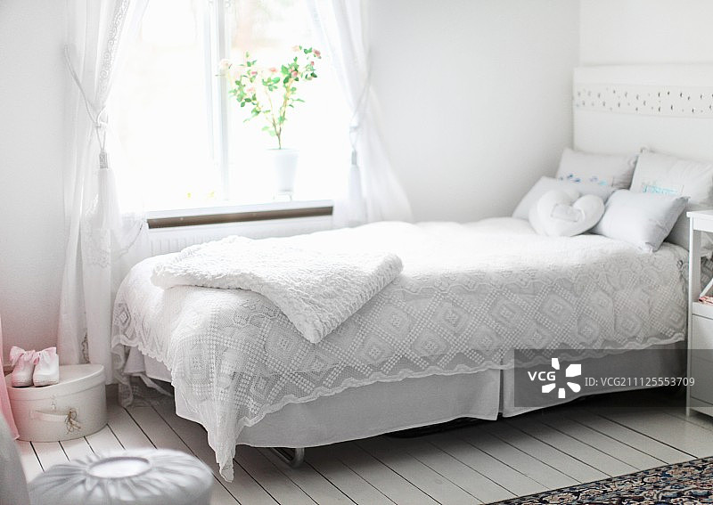 在质朴的室内，窗户下的床上铺着白色的花边床罩图片素材