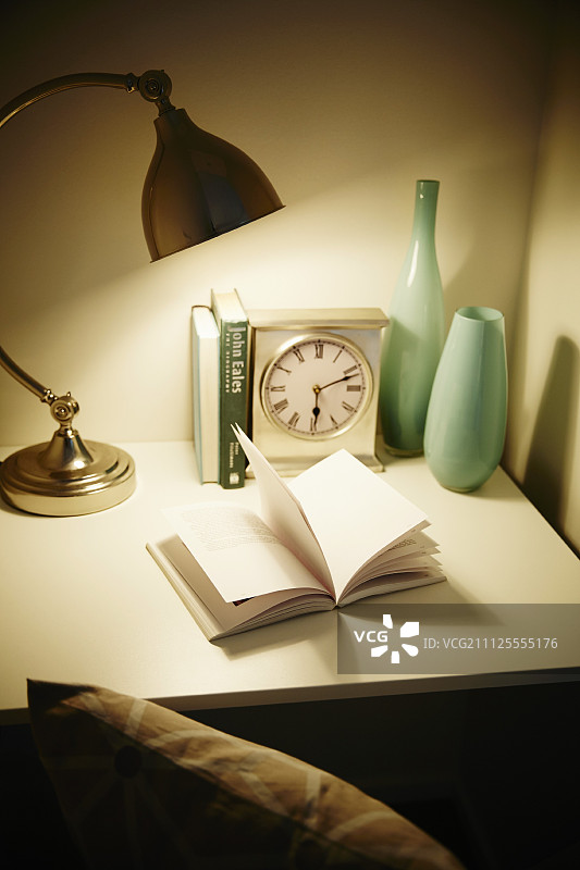 打开书下面的台灯桌上有钟和花瓶图片素材