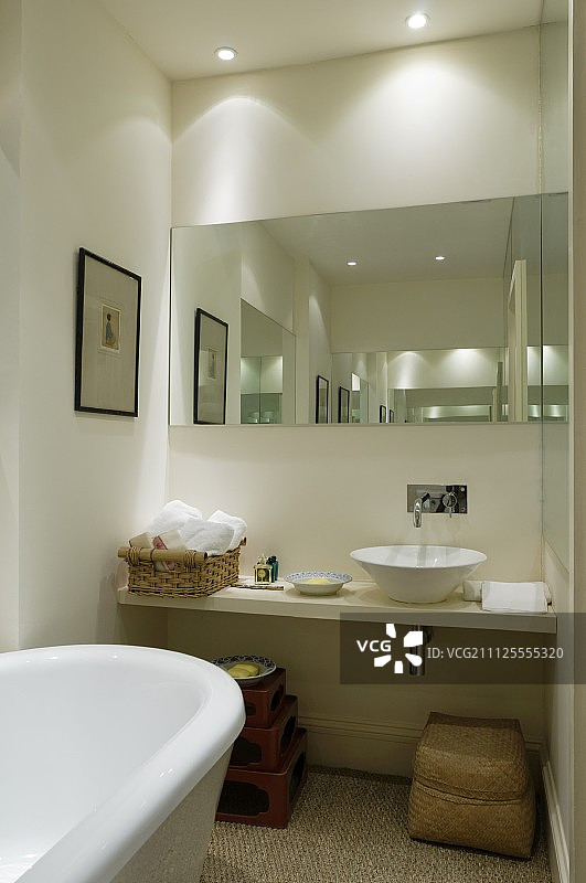 狭窄的浴室有镜子，戏剧性的照明，浮动盥洗架和台面盆图片素材