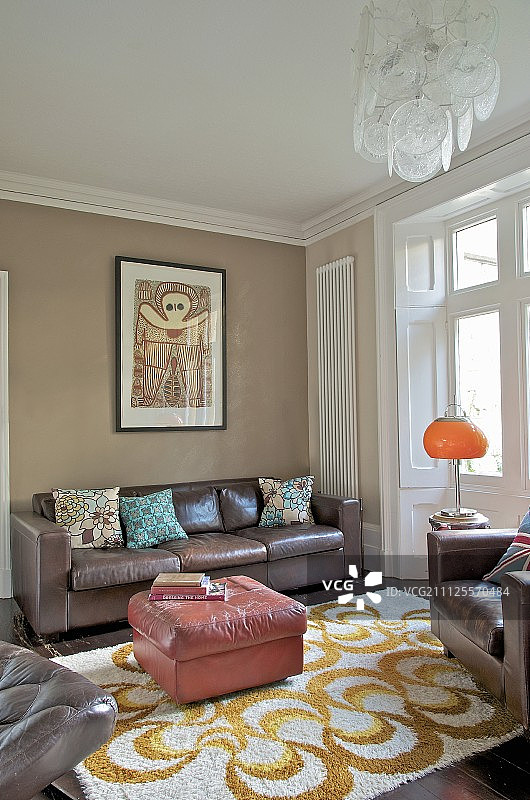 在传统的室内，有图案的地毯和棕色皮革沙发和扶手椅图片素材