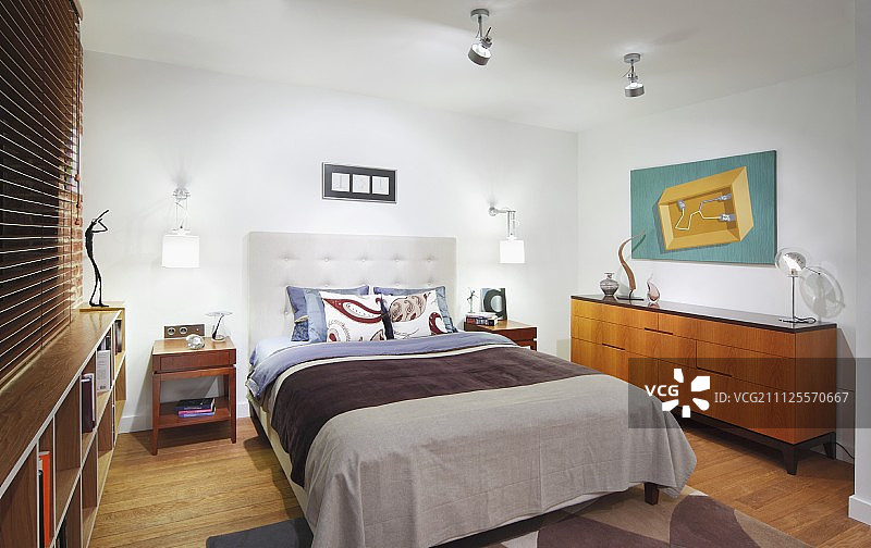 现代卧室中的双人床配有软垫床头板，旁边是50年代风格的餐具柜图片素材