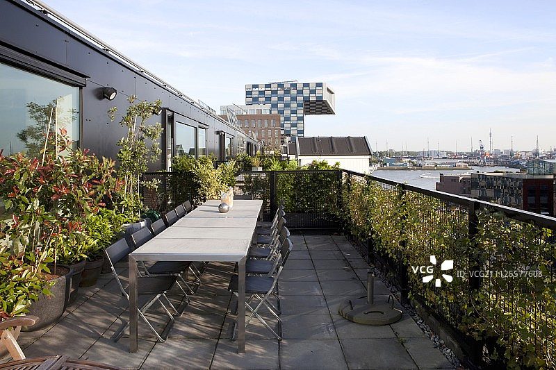 在顶层屋顶平台上的桌子和折叠椅与城市的观点图片素材