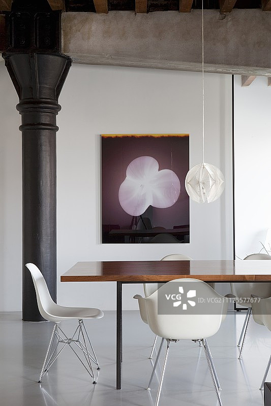 在修复的阁楼公寓中，白色经典椅子围绕着餐桌，墙上挂着现代艺术品图片素材