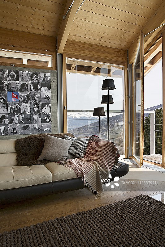 皮沙发下面的照片在墙上旁边的一组标准灯，在全景窗户前的木屋内饰图片素材