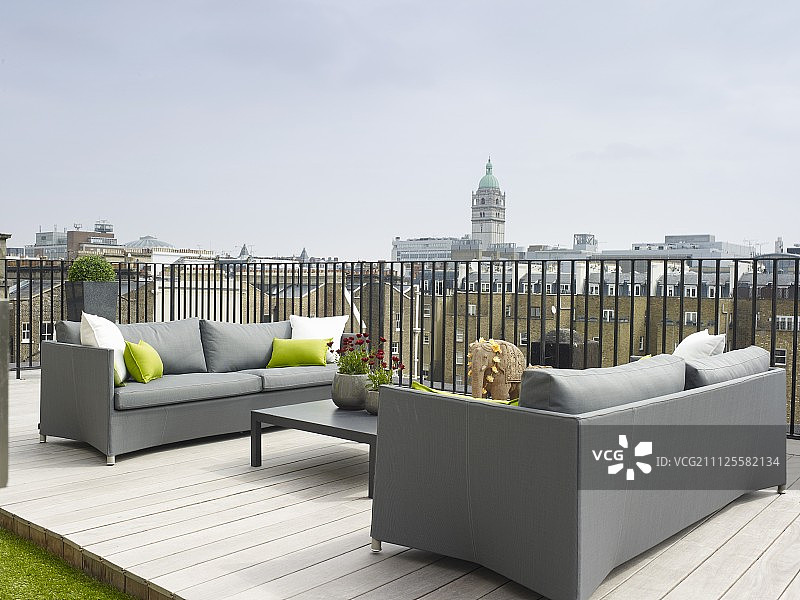 优雅的灰色沙发和低矮的咖啡桌在屋顶露台与木制甲板图片素材