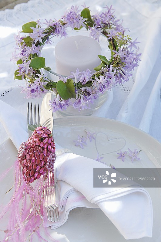 烛台上装饰着紫色的花环和用闪闪发光的粉红色珠子做成的鸟装饰品图片素材