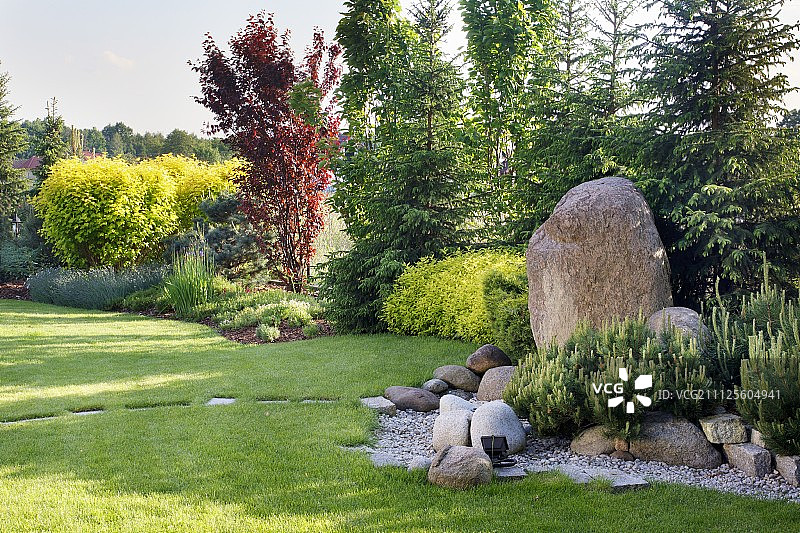 花园景观与巨石和踏石在草坪和森林的观点图片素材