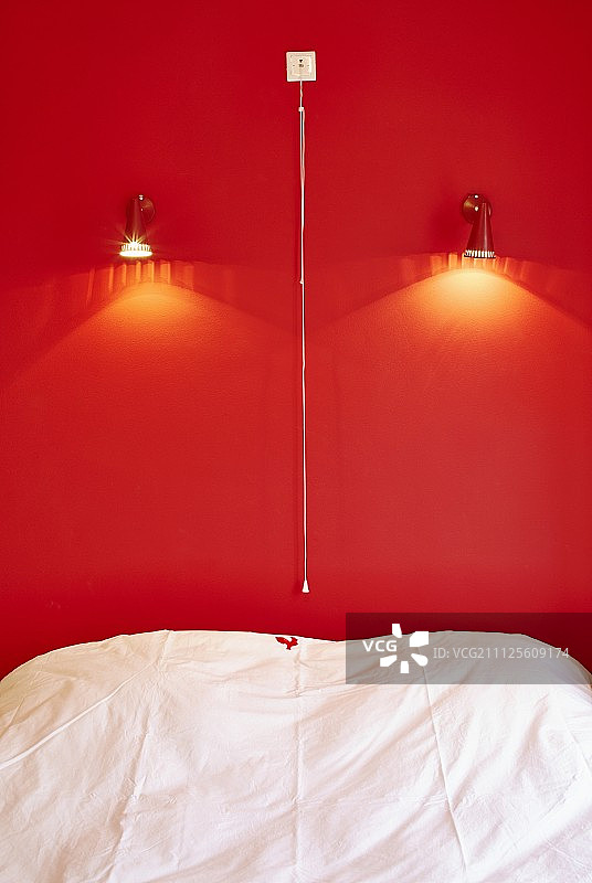 床在聚光灯下亮红色的墙上图片素材