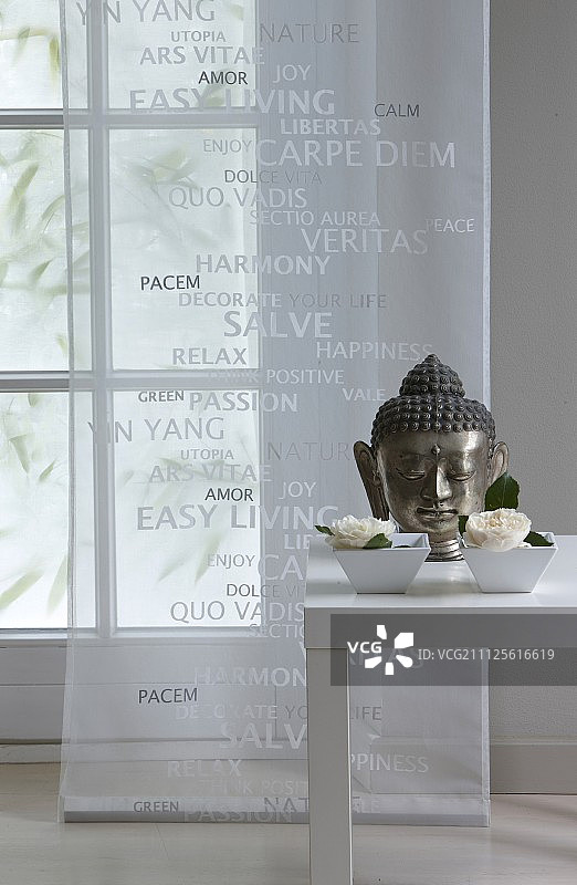 在透明的窗板前，用瓷碗装饰的桌子上有佛像和鲜花图片素材