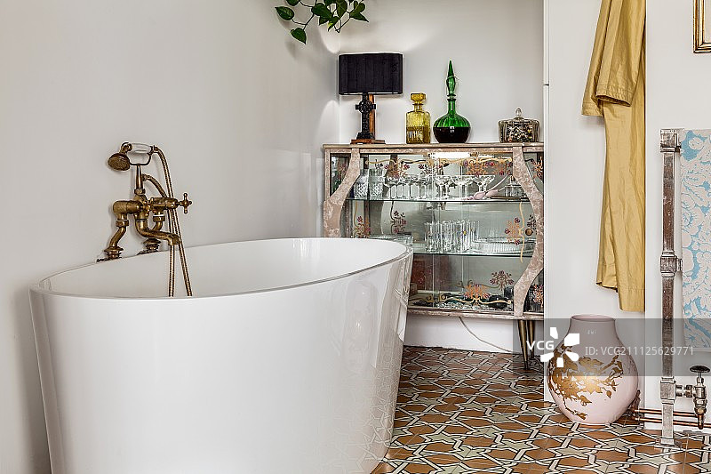 现代，独立的浴缸与复古风格的水龙头配件在复古的玻璃展示柜图片素材