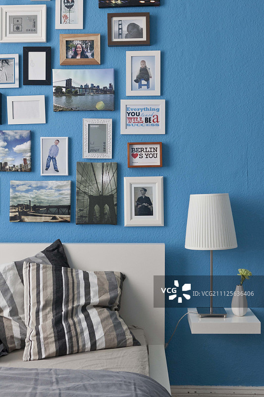 蓝色的卧室墙上挂着各种沙龙风格的相框图片素材