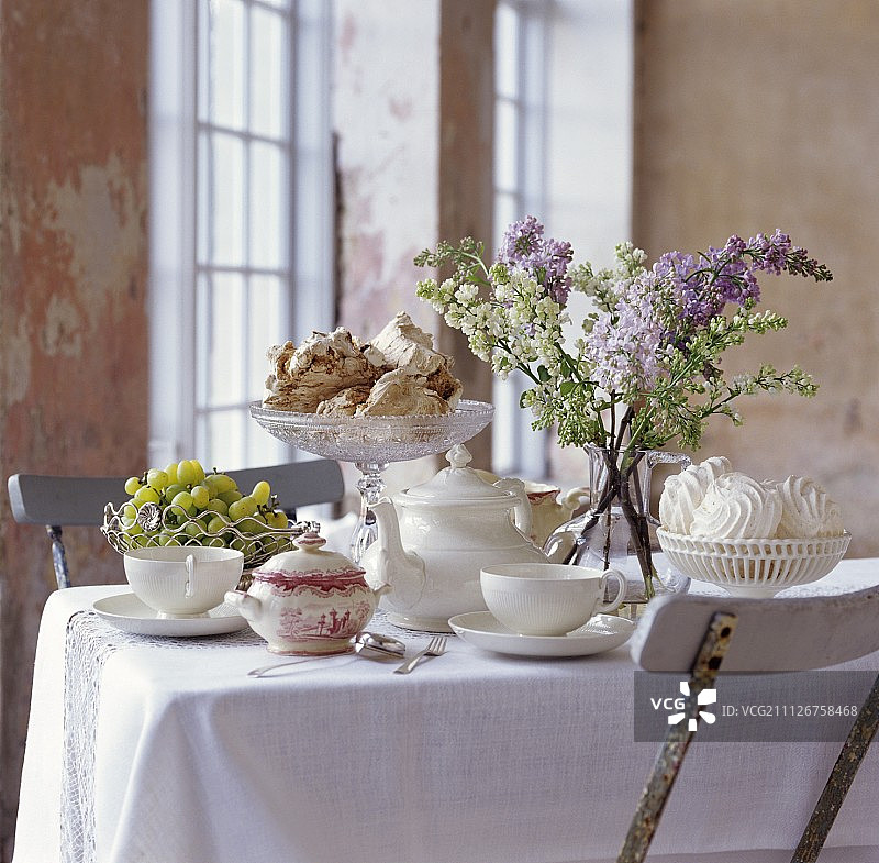 桌子上摆好了茶，有蛋白霜、葡萄和一束紫丁香图片素材