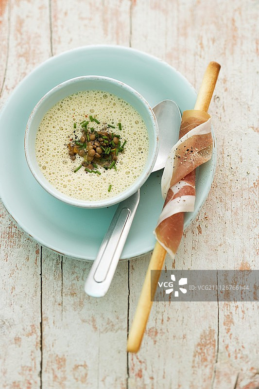 泡沫扁豆汤和裹着帕尔玛火腿的面包棒图片素材