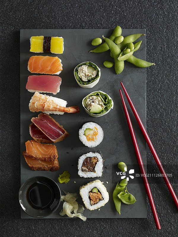 手握寿司、加州卷、寿司和石盘上的生鱼片图片素材