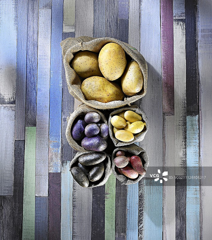 五颜六色的木质表面上装着各式各样的土豆(从上面看)图片素材