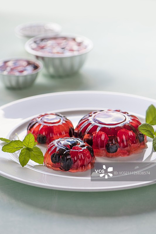 果冻和红色水果在白色盘子上装饰薄荷图片素材