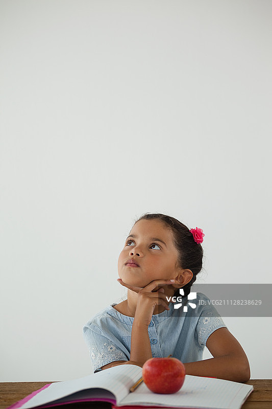 沉思的年轻女孩坐在白色的背景图片素材