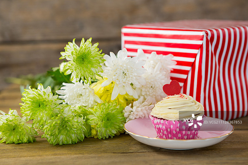 礼品盒和鲜花的特写与纸杯蛋糕在板上的木板图片素材