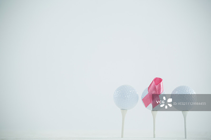 白色背景下高尔夫球上的粉色乳腺癌意识丝带图片素材
