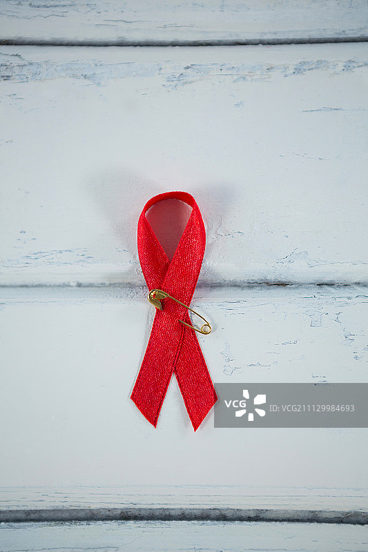 头顶上白色木桌上的红色艾滋病意识丝带图片素材